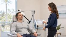 Patient receiving TMS treatment while a clinician monitors the session